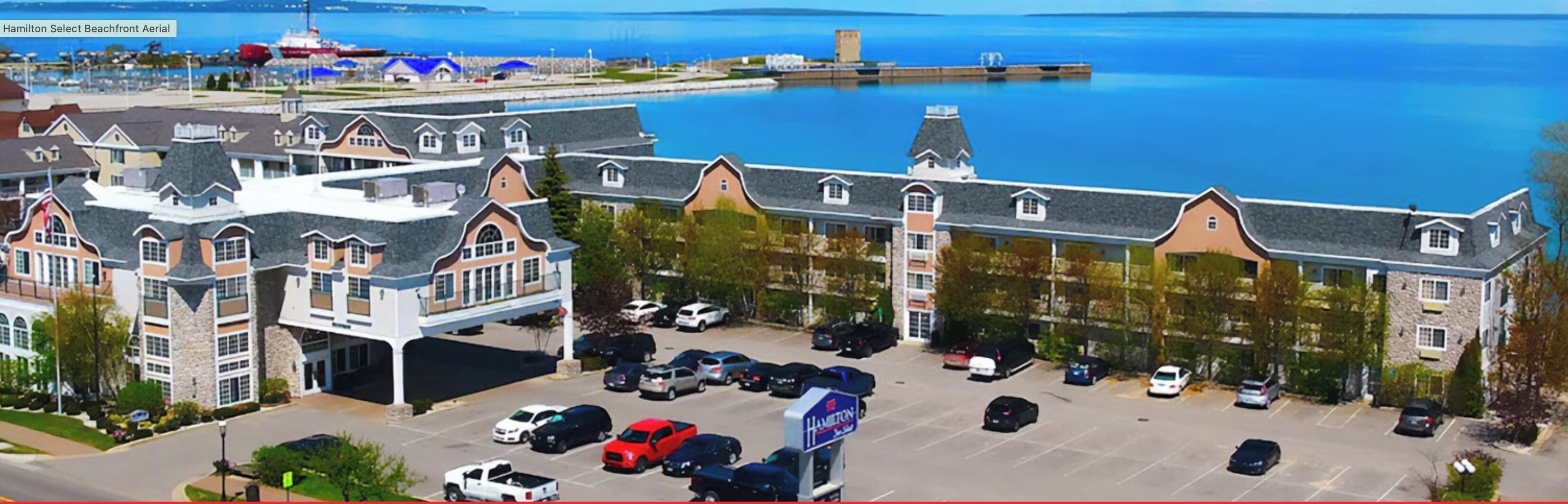 A hotel with a parking lot and a view of the water.