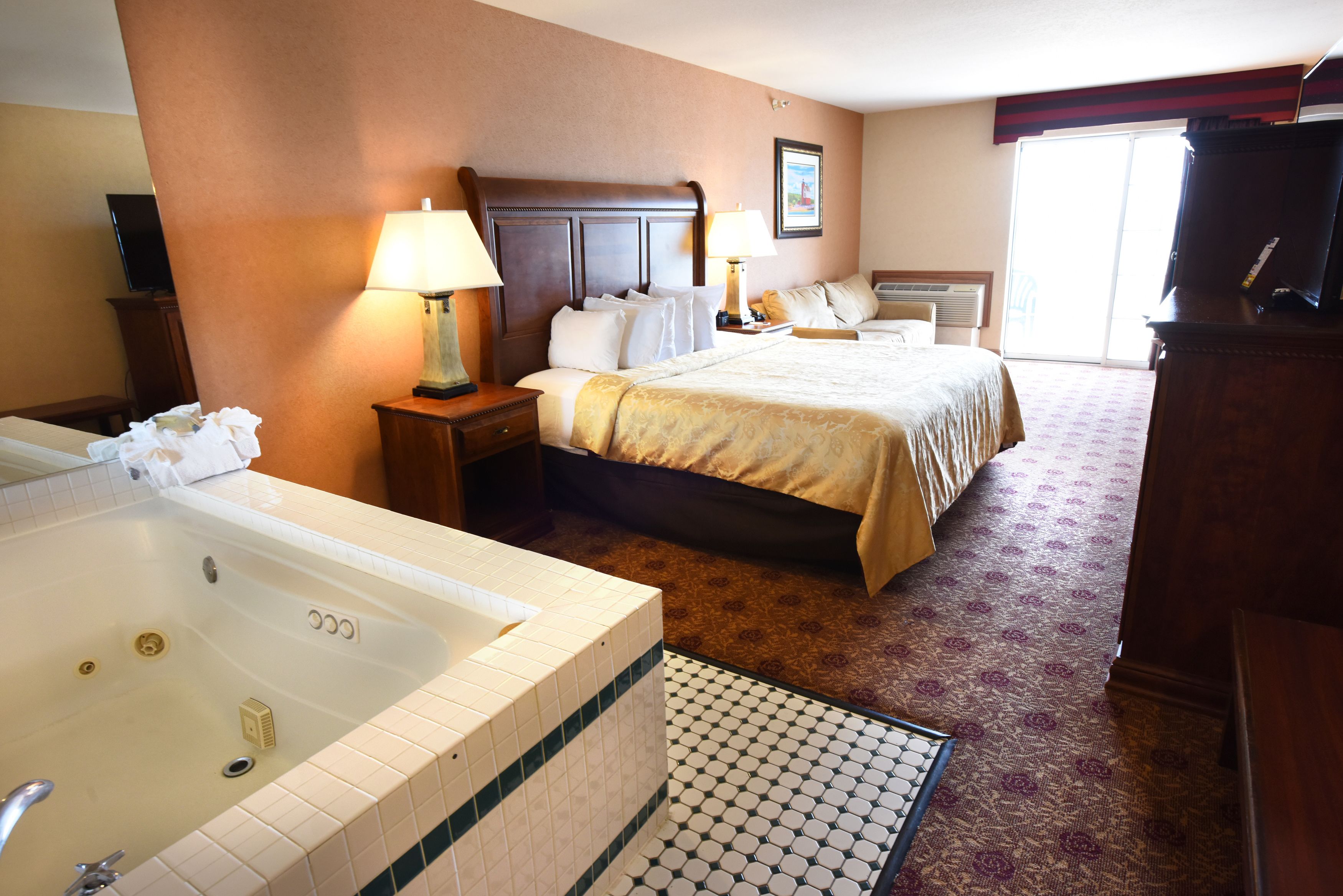 A hotel room with a large bed, a separate bathroom with a bathtub, and a television.