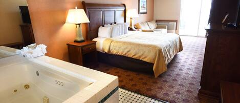 A hotel room with a large bed, a separate bathroom with a bathtub, and a television.
