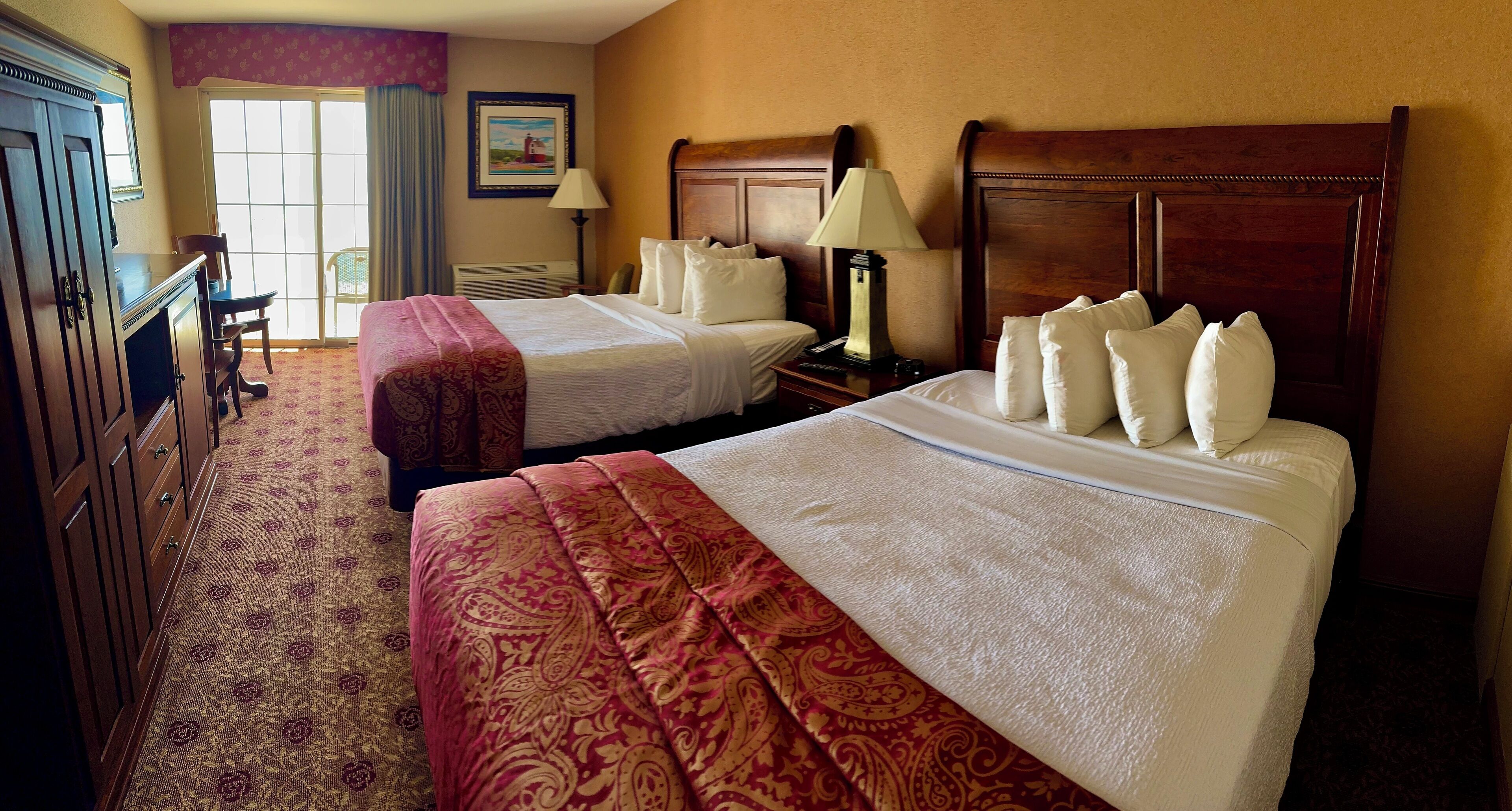 A hotel room with two beds, a desk, and a chair.
