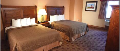 A hotel room with two beds, a nightstand with a lamp, a framed picture on the wall, and a window with curtains.