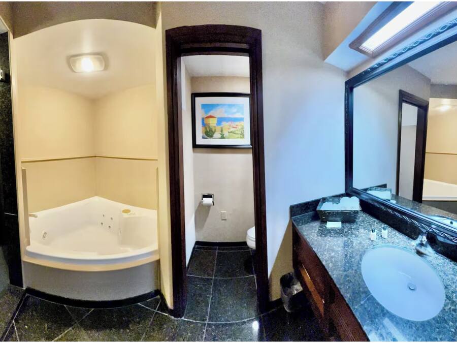 A bathroom with a large bathtub, a sink, and a mirror.
