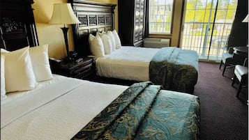 A hotel room with two beds, a nightstand, a lamp, and a view of the outside through a large window.