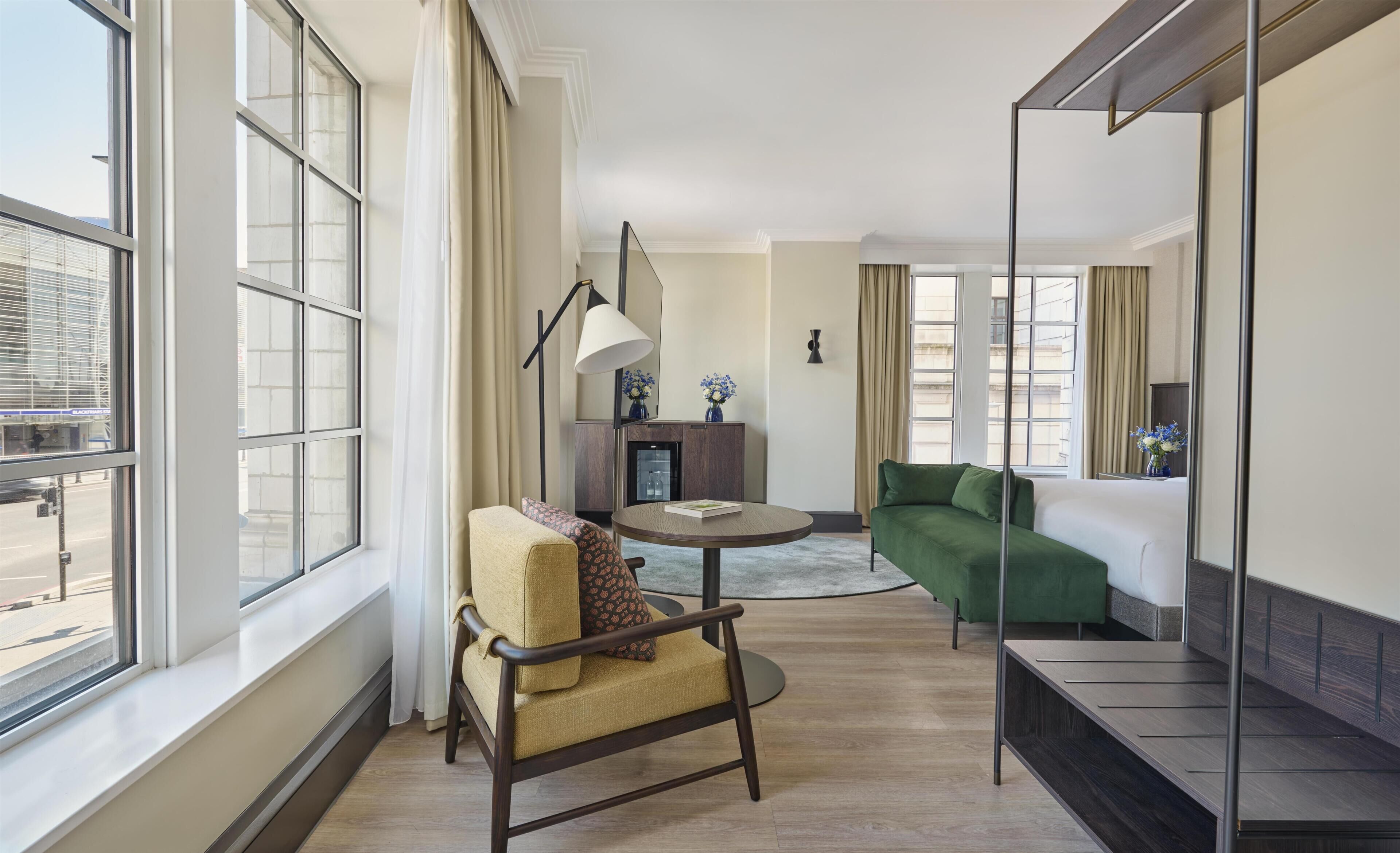 A modern hotel room with a sofa, armchair, and a small table.