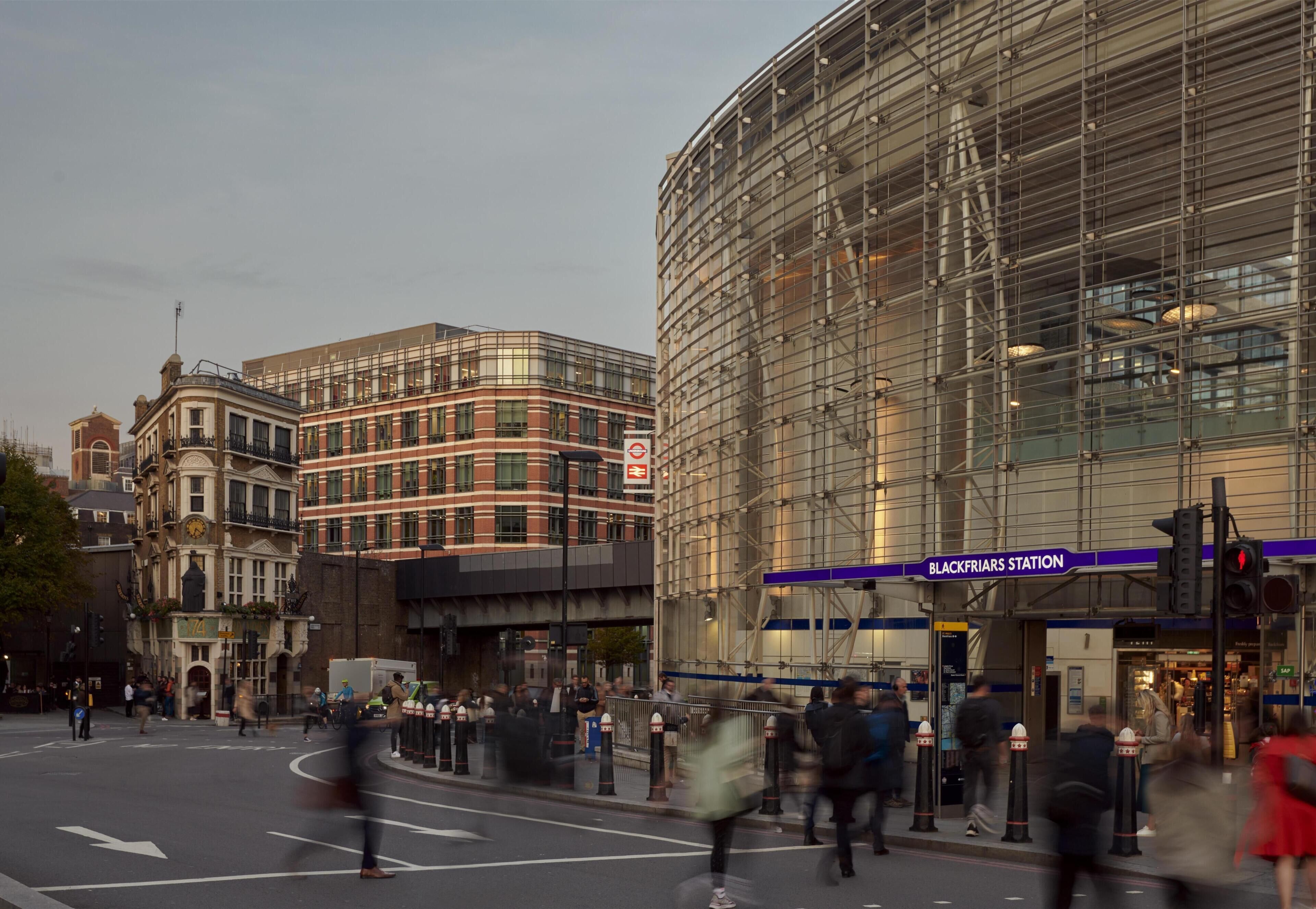 A street view with a modern building labeled 'BLACKFRIARS STATION' and a historic building with a clock tower.