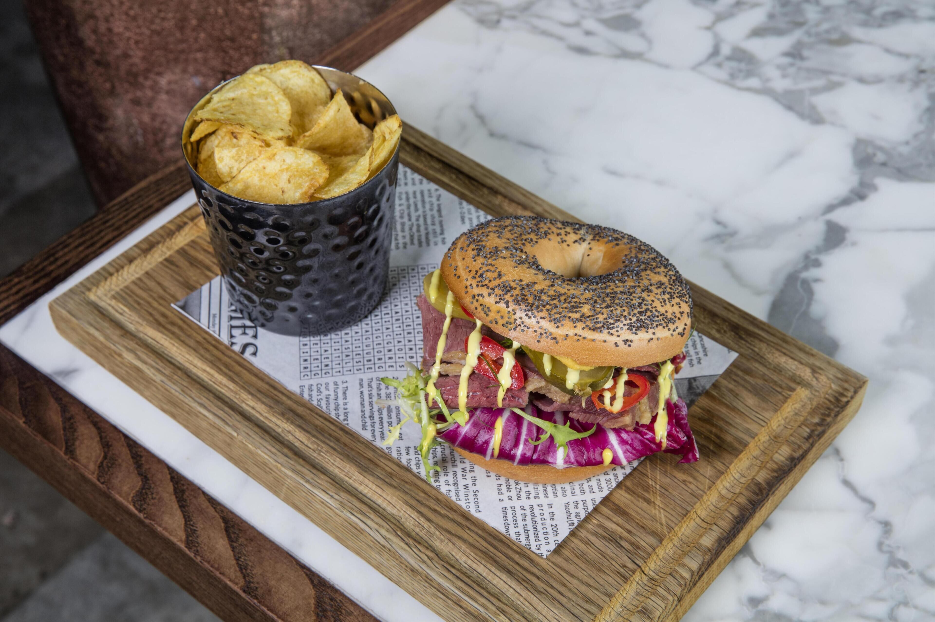 A meal with a burger and chips on a wooden board.