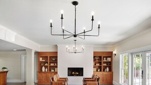 A spacious living room with a fireplace, two leather sofas, a coffee table with apples, and a chandelier. - Inn At Sonoma - A Four Sisters Inn (Sonoma)