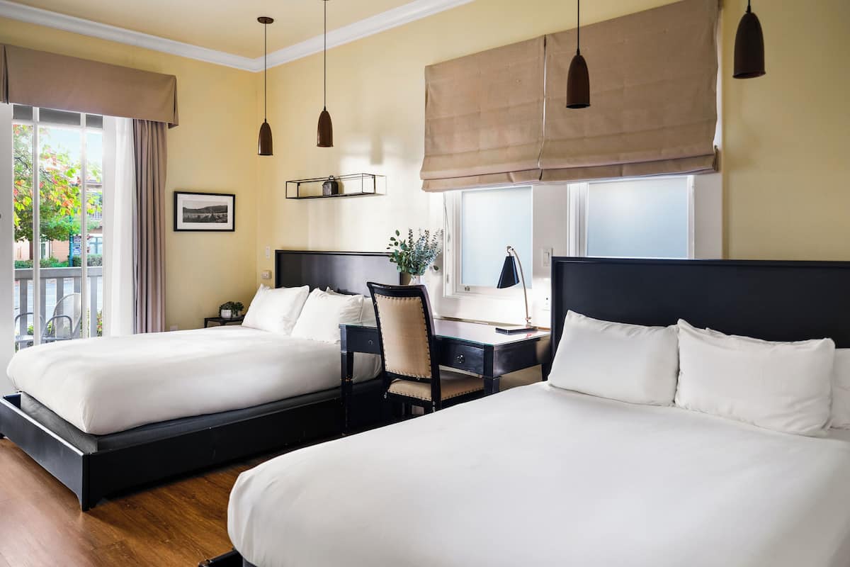 A hotel room with two beds, a desk, and a chair.
