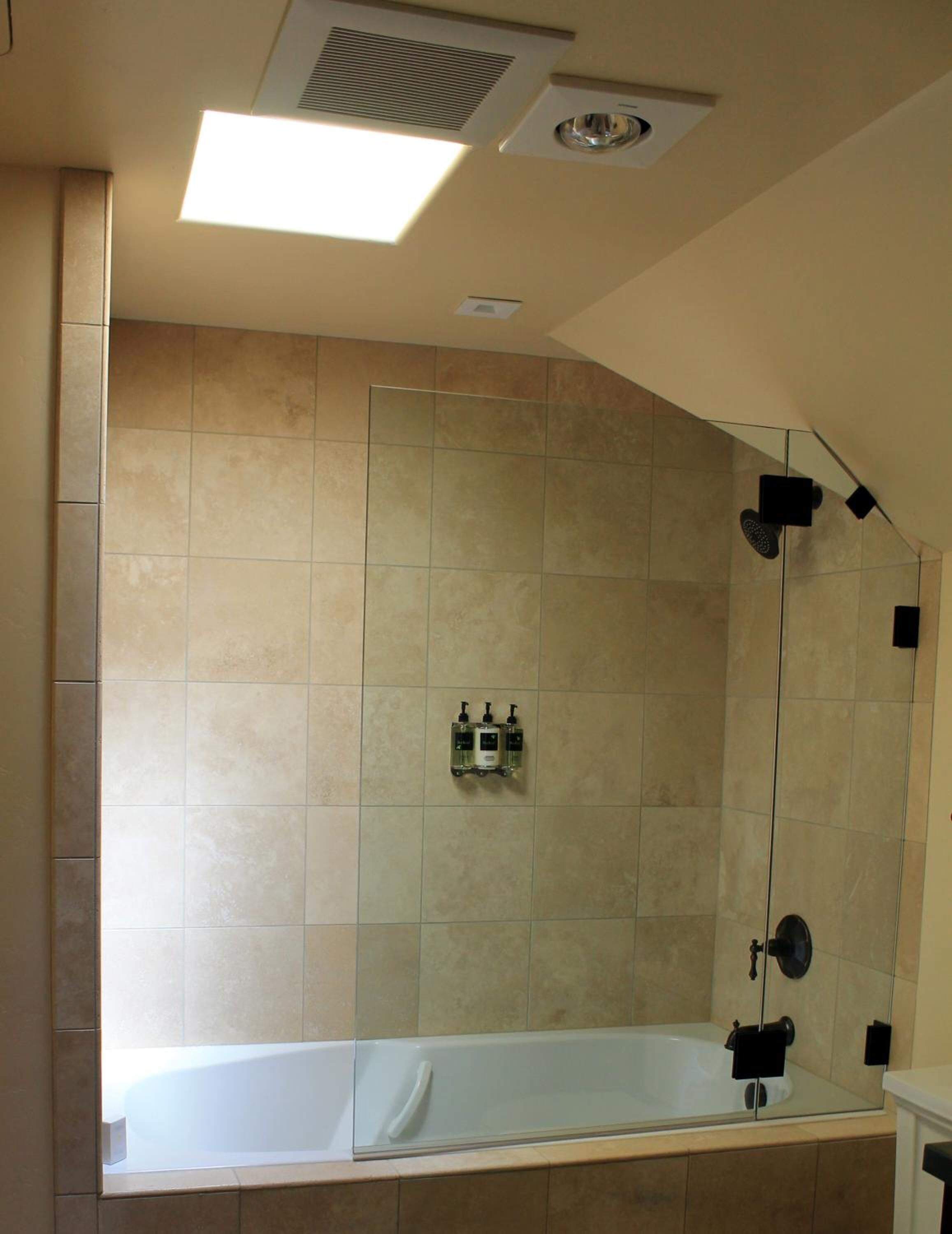 Een badkamer met een bad, een douche en een dakraam.