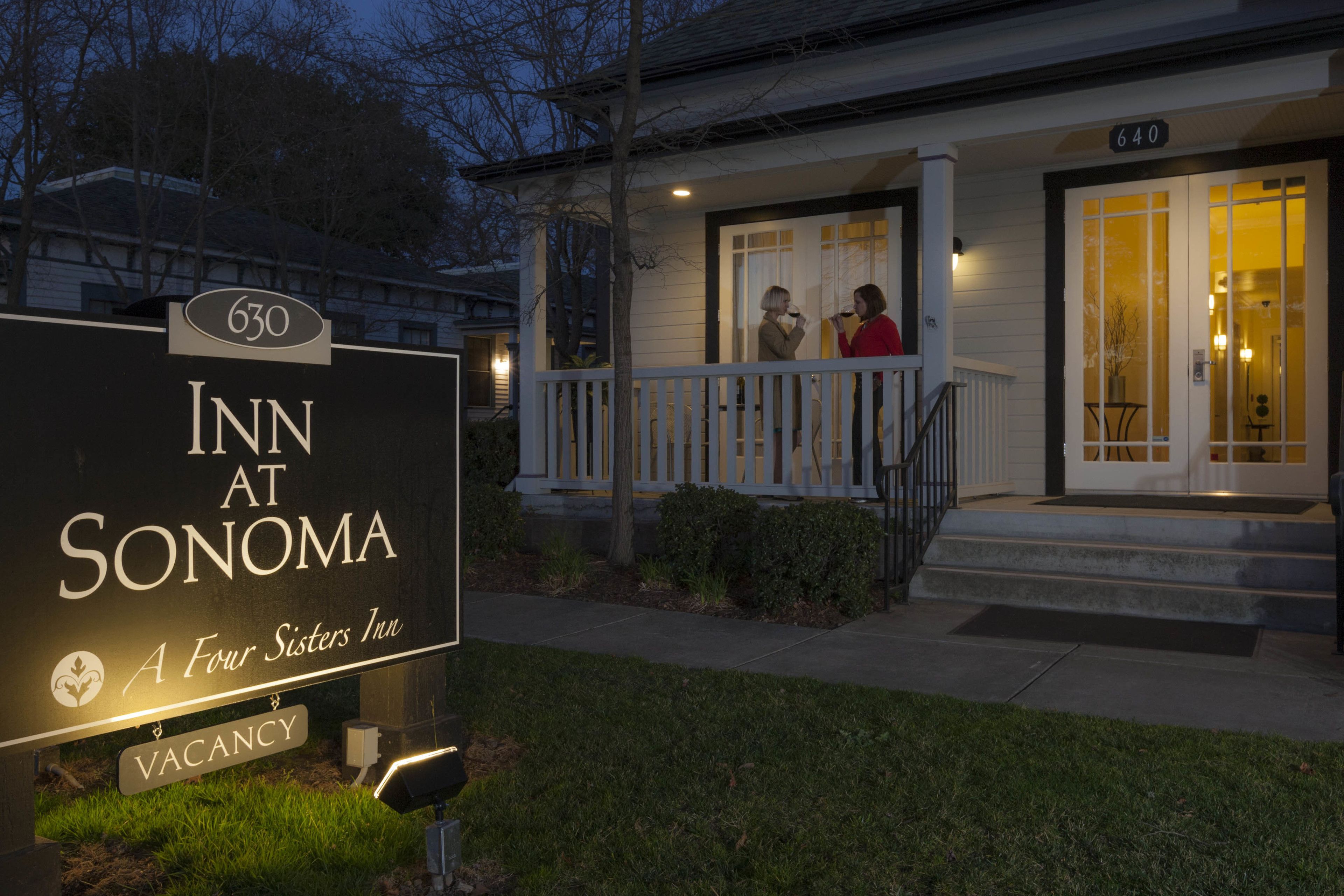 Une enseigne d’hôtel avec les inscriptions « INN AT SONOMA » et « A Four Sisters Inn », une enseigne indiquant « CHAMBRES LIBRES », et un bâtiment doté d’un porche et d’un escalier.