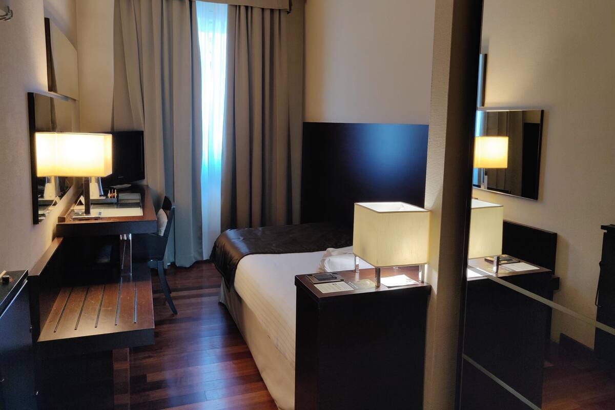 Una habitación de hotel con cama, escritorio, silla y televisor.