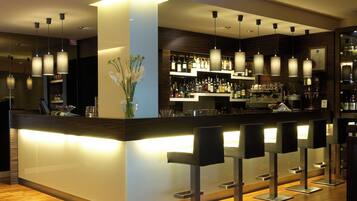 A modern bar area with a central counter, multiple hanging pendant lights, and bar stools.