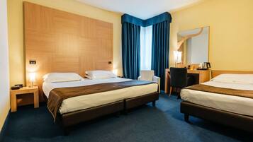 A hotel room with two beds, a desk, a chair, and a large mirror.