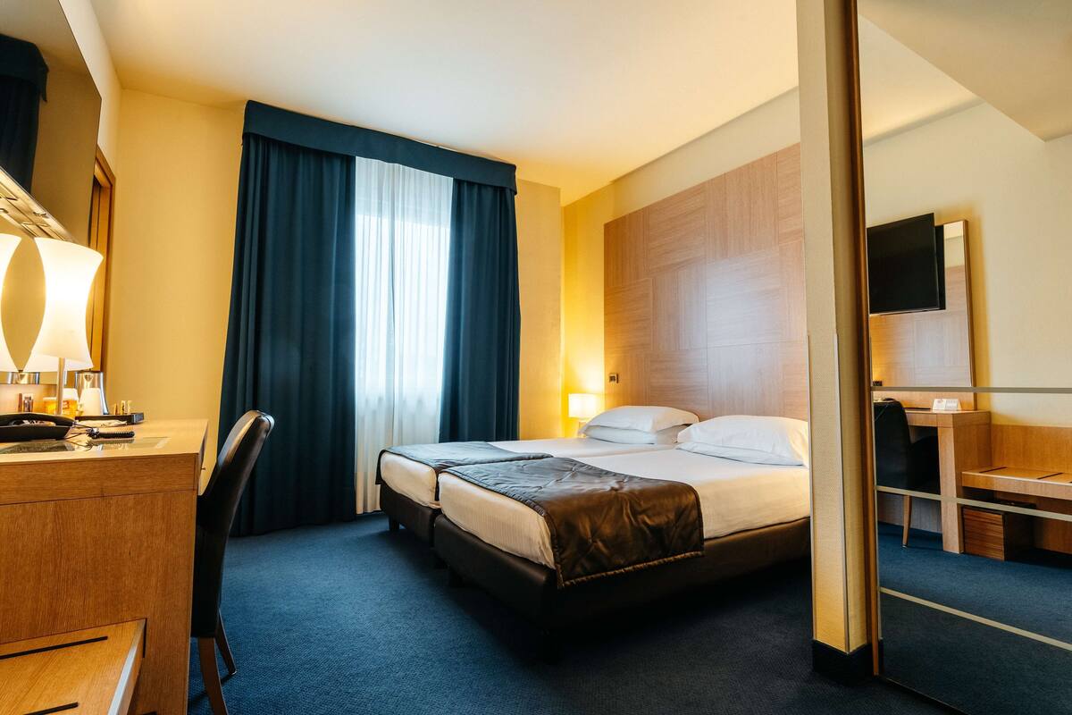 Una habitación de hotel con cama, escritorio, silla y televisión.