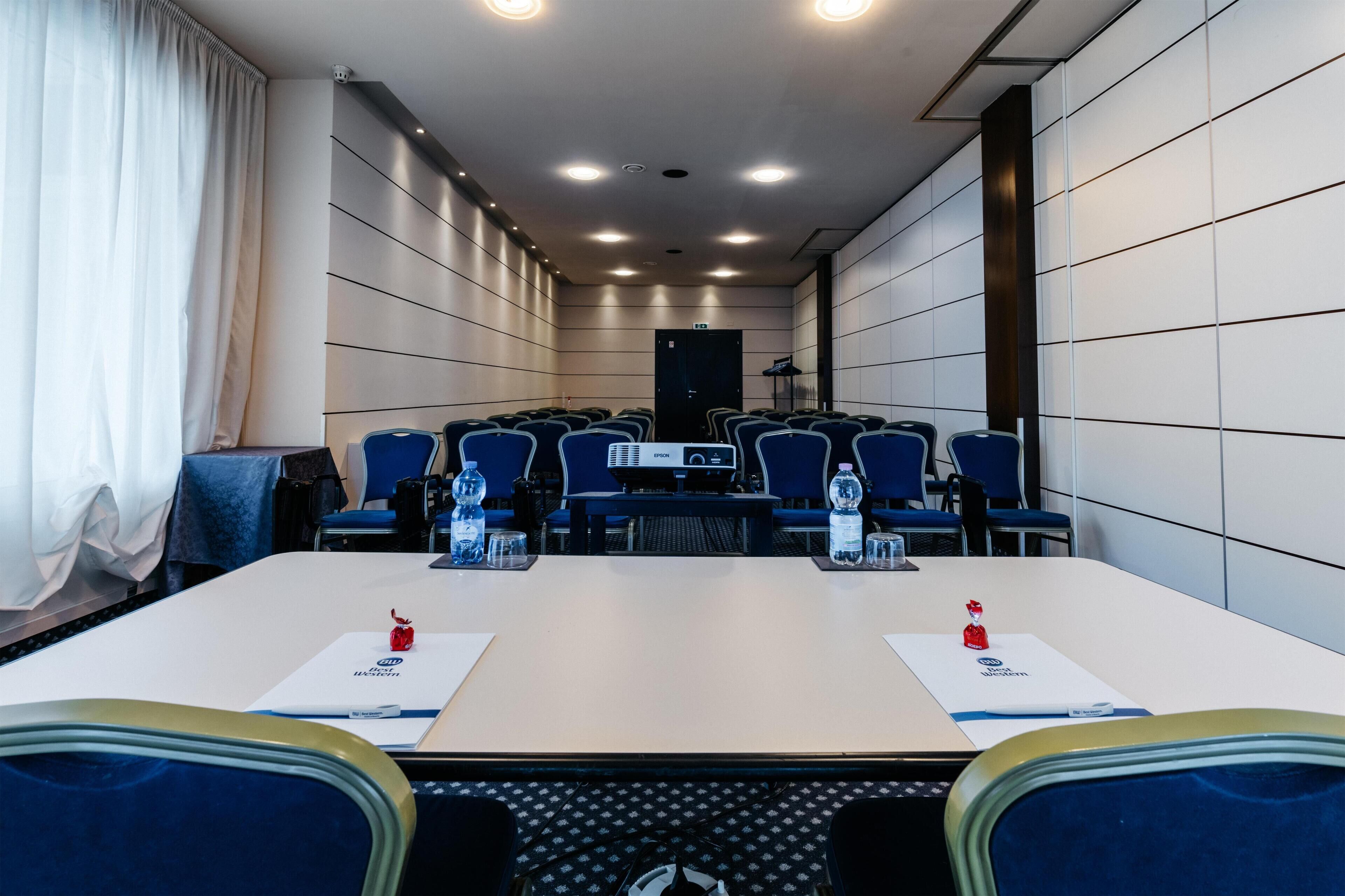 A conference room with a long table, blue chairs, and a projector.