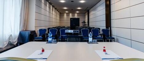 A conference room with a long table, blue chairs, and a projector.