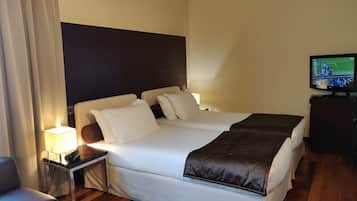 Una habitación de hotel con cama, mesitas de noche, televisor y lámpara.