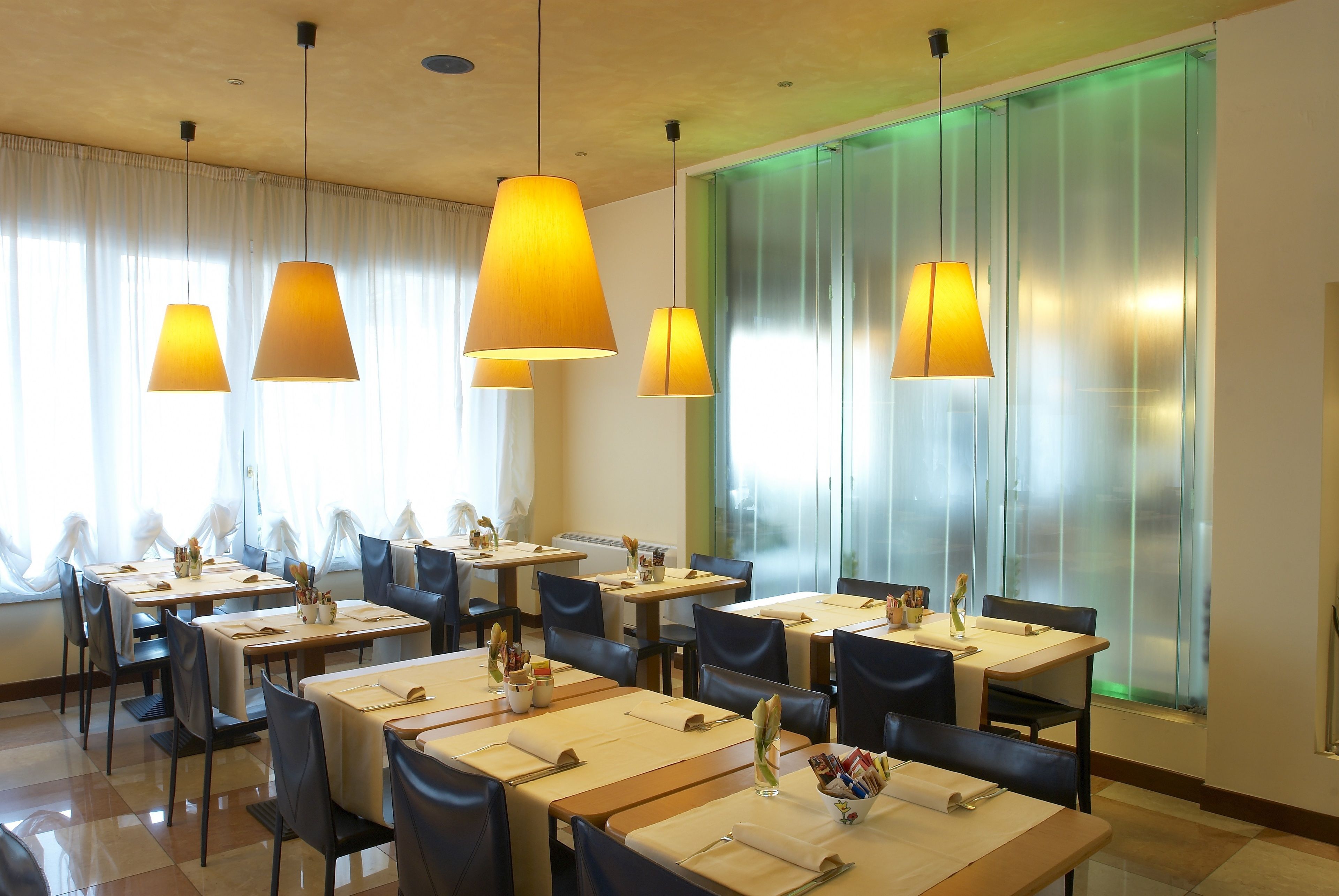 Un restaurant doté de nombreuses tables, de chaises et de luminaires suspendus.