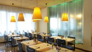 Un restaurant doté de nombreuses tables, de chaises et de luminaires suspendus.