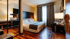 Ein Hotelzimmer mit Bett, Schreibtisch und Spiegel.