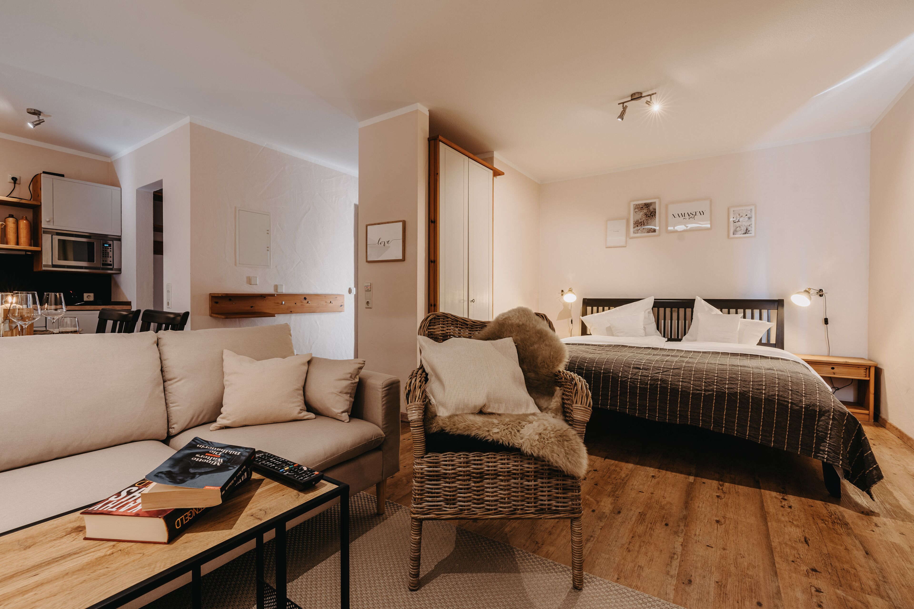 A bedroom with a bed, a chair, a sofa, a bedside table, and a nightstand.
