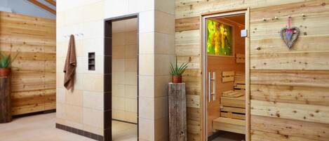 Ein Wellnessraum mit Holzwänden, Fliesenboden, einer Holzbank und einer Pflanze.