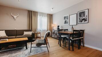 Ein modernes Wohnzimmer mit einer Couch, einem fellbezogenen Sessel, einem Esstisch mit Stühlen, einer Kuhskulls Dekoration an der Wand und gerahmten Bildern.