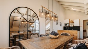 A dining area with a wooden table, wicker chairs, and a large window with a geometric design. - MANA LISA Boutiquehotel (Lauda)