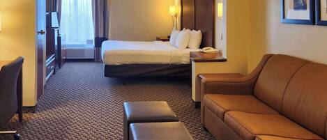 Habitación de hotel con cama, sofá, escritorio y silla.