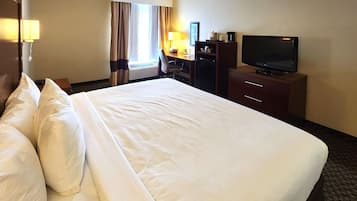 Quarto de hotel com uma cama grande, uma escrivaninha com cadeira, uma televisão e uma luminária de mesa.