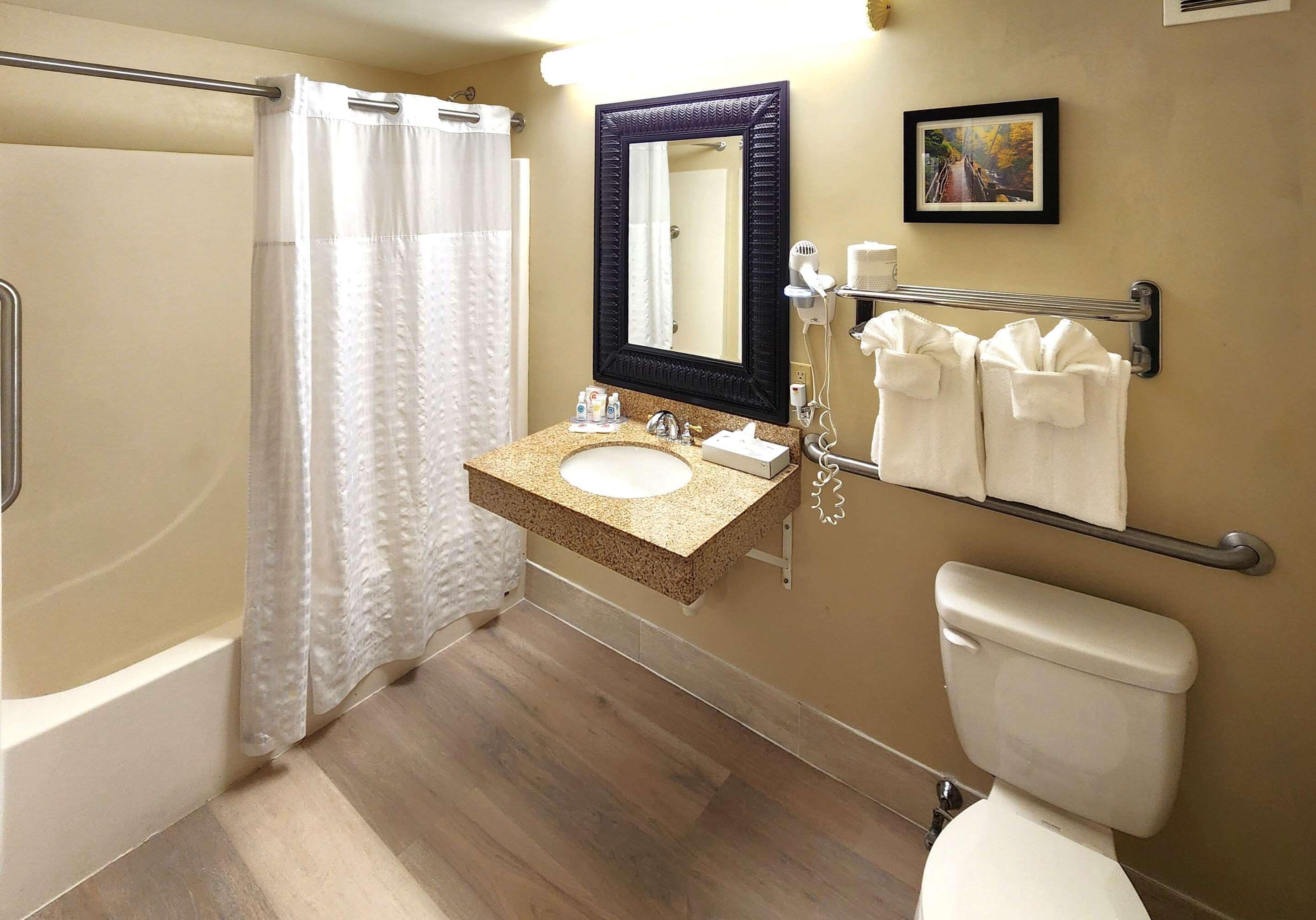 Une salle de bain comprenant une baignoire, un lavabo avec un miroir au-dessus, des toilettes et un porte-serviettes avec des serviettes.