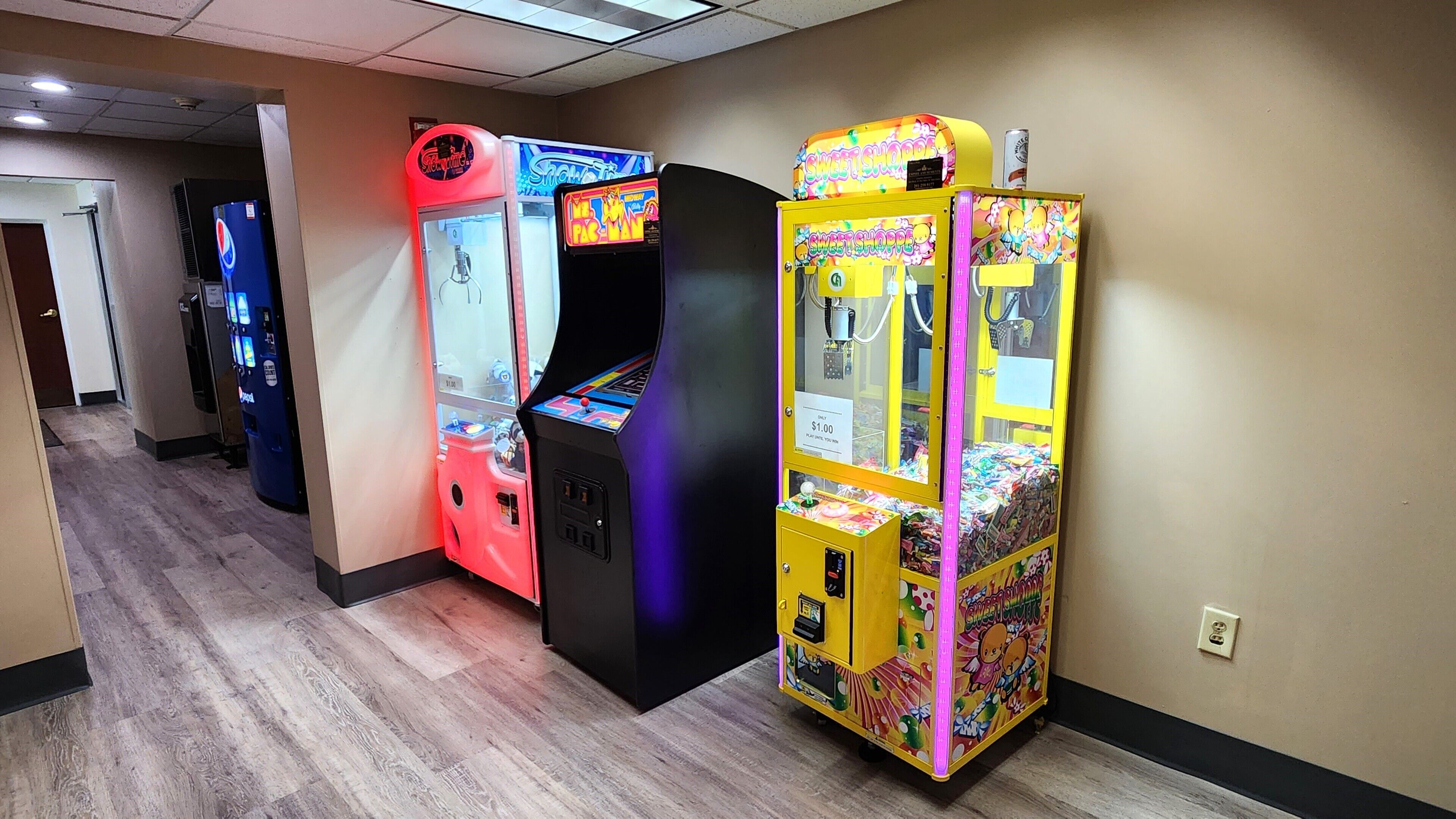 Un pasillo con máquinas recreativas, incluyendo una roja y una amarilla, y una máquina expendedora.