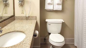Un baño con encimera de granito, lavabo, inodoro y toallero con toallas.
