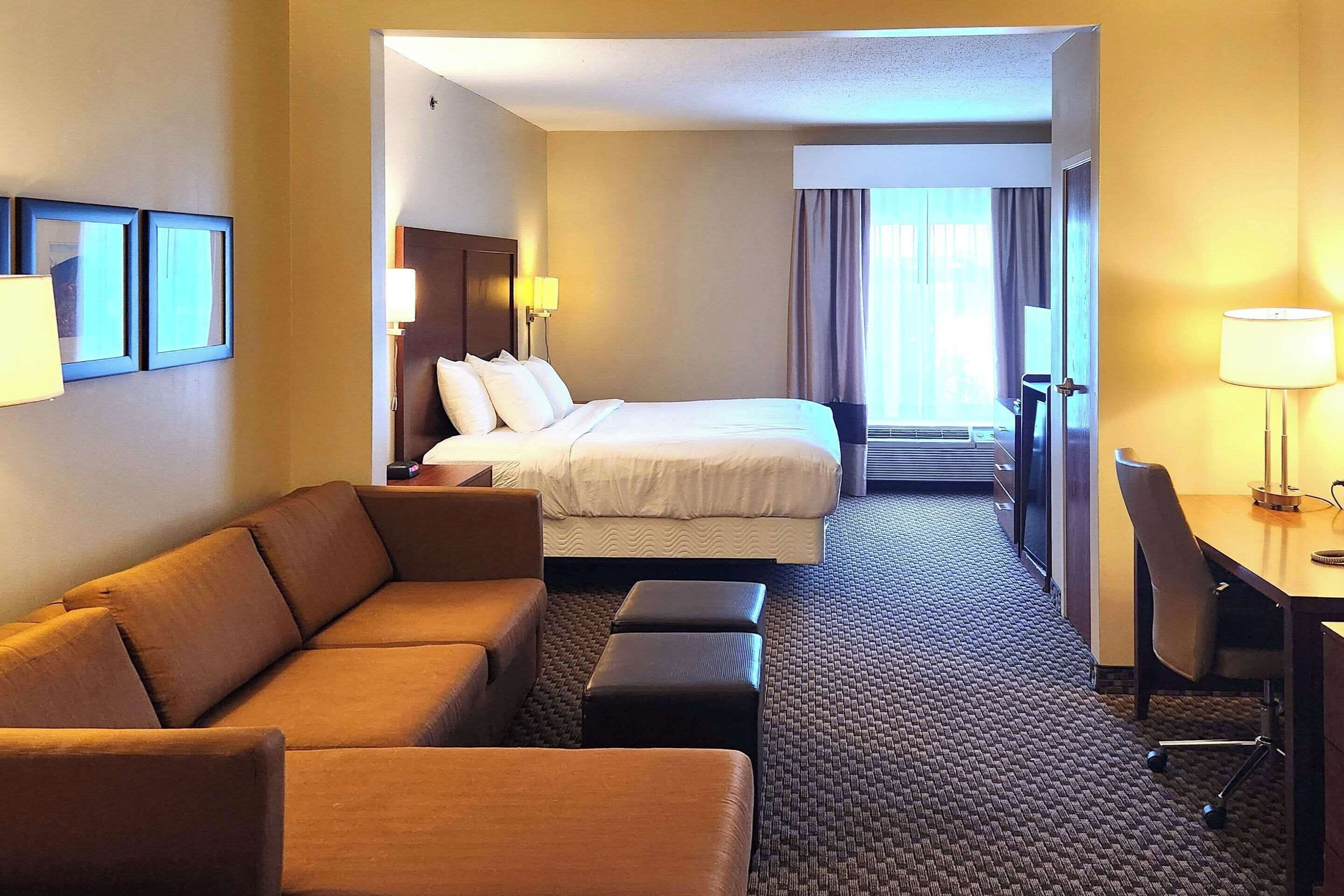 Una habitación de hotel con cama, sofá, escritorio y una silla.