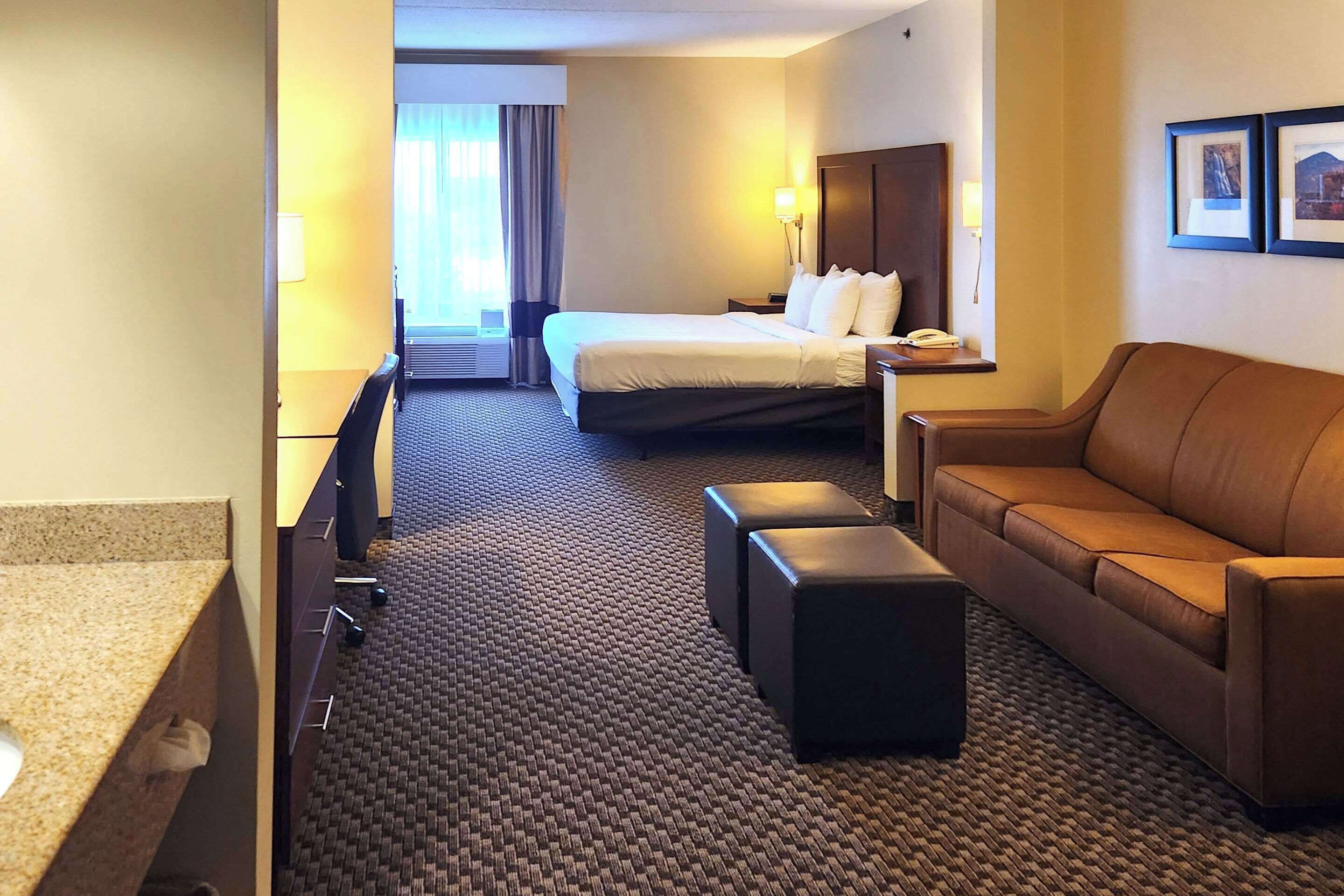 A hotel room with a bed, a sofa, a desk, and a bathroom.