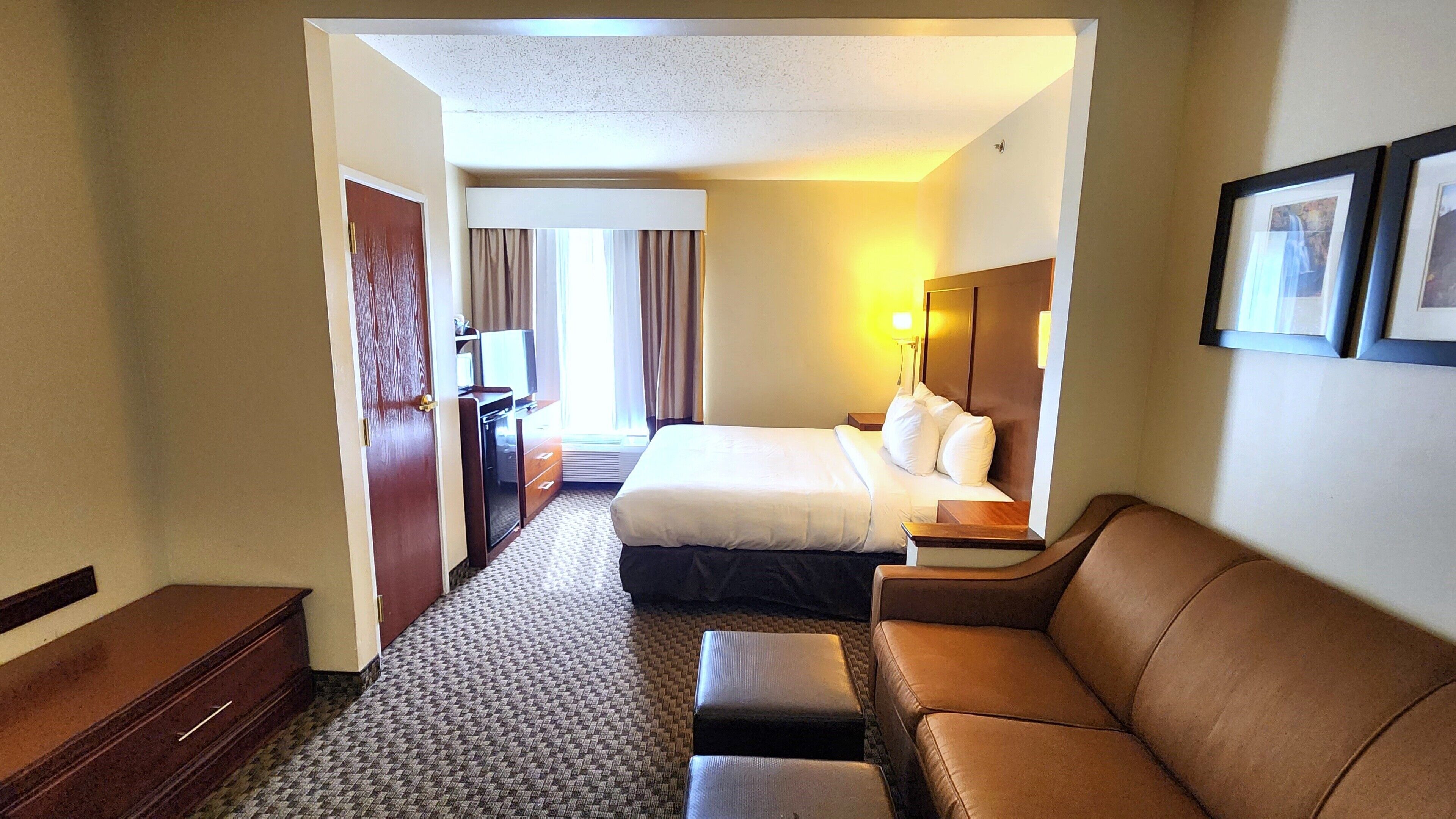 A hotel room with a bed, a sofa, a desk, and a chair.
