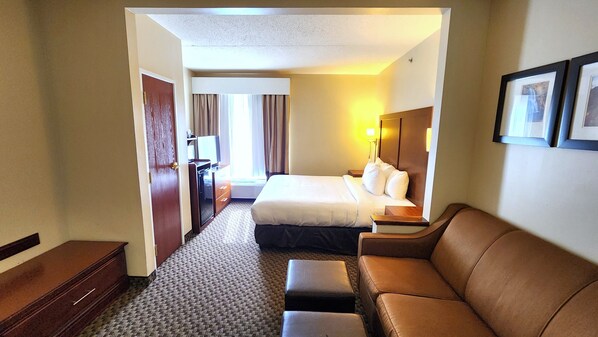 A hotel room with a bed, a sofa, a desk, and a chair.