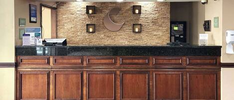 A reception desk with a wooden panel design, a stone wall backdrop, and a large crescent moon logo.