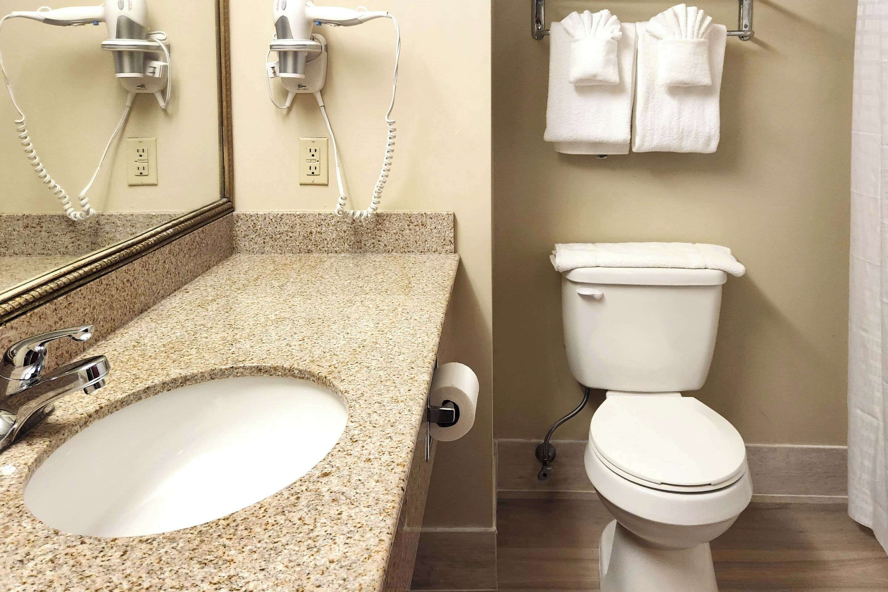 A bathroom with a sink, a toilet, and a hairdryer mounted on the wall.