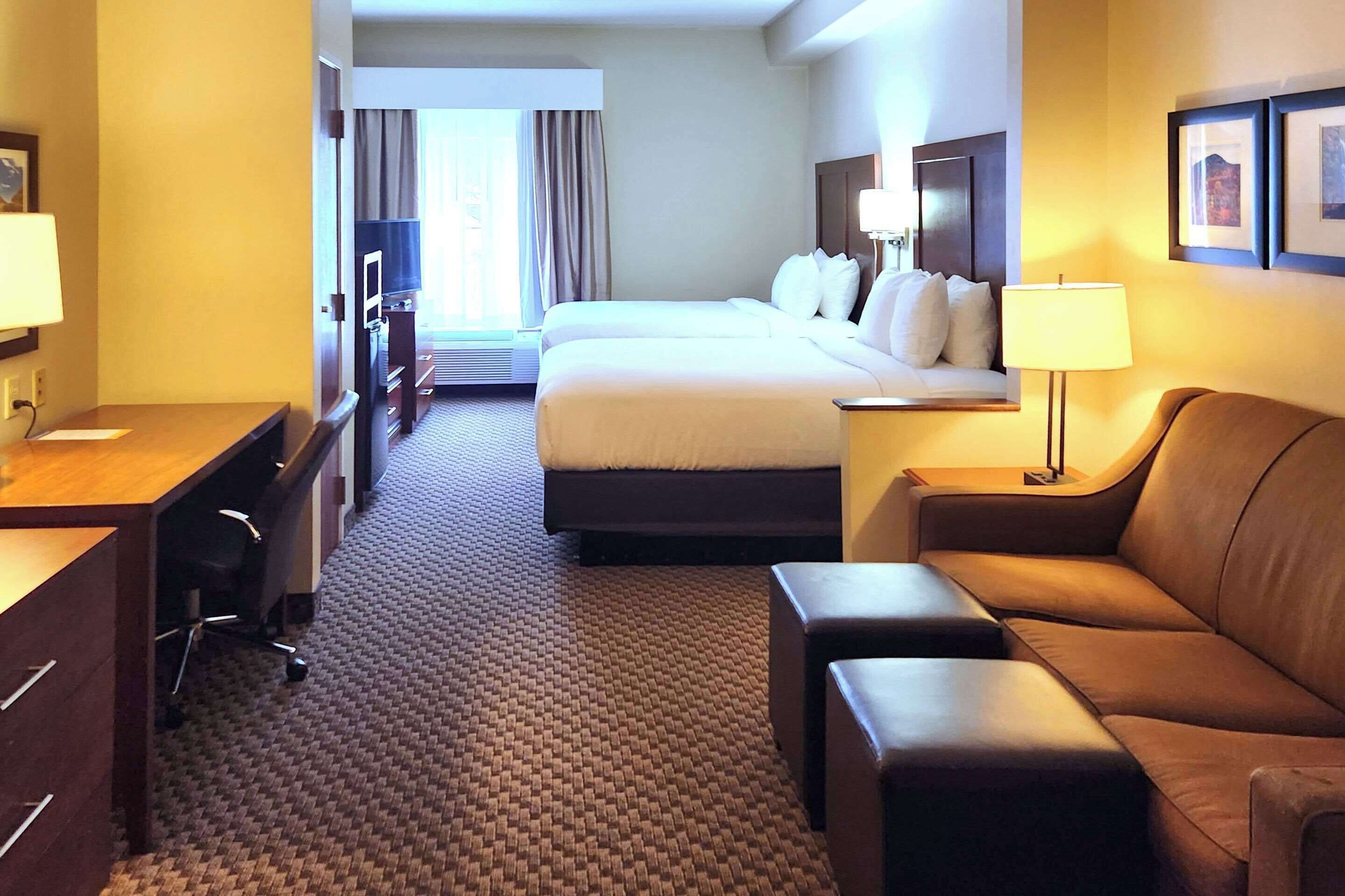 Ein Hotelzimmer mit einem Bett, einem Schreibtisch, einem Sessel, einer Couch und einer Lampe.
