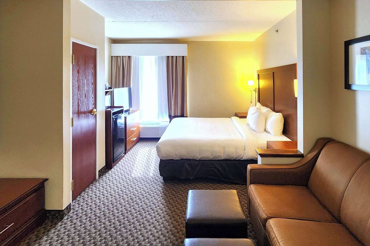 Una habitación de hotel con cama, sofá, escritorio y televisión.