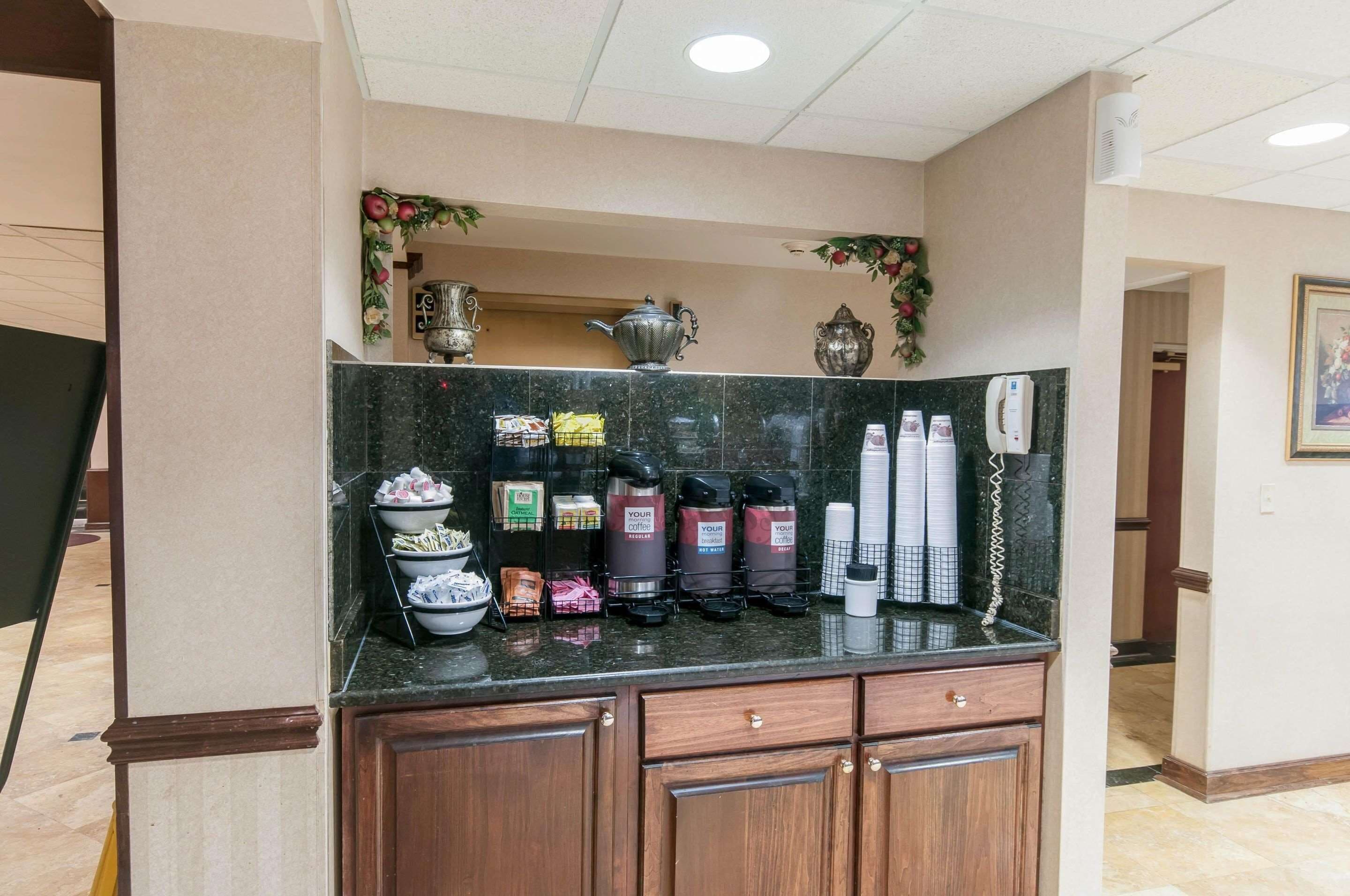 A hotel reception area with a marble counter, coffee makers, and a telephone.