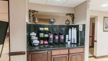 A hotel reception area with a marble counter, coffee makers, and a telephone.