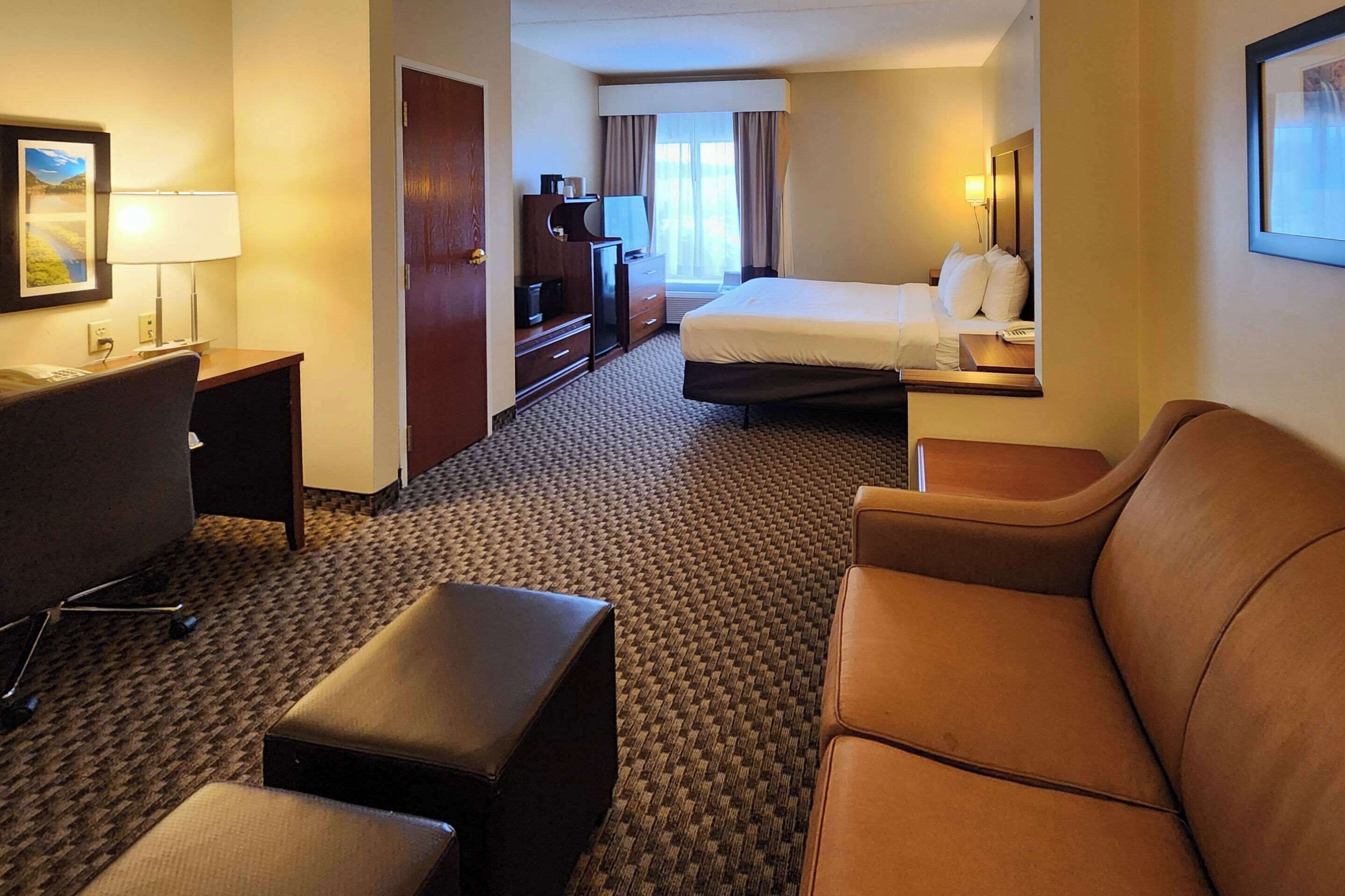 Una habitación de hotel con cama, escritorio, silla, sofá y televisión.