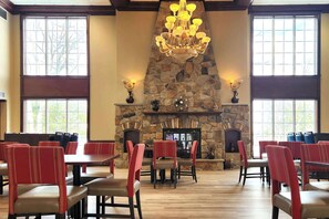 A dining area with stone fireplace, red upholstered chairs, and large windows. - Comfort Inn & Suites Mount Pocono (Pocono Summit)