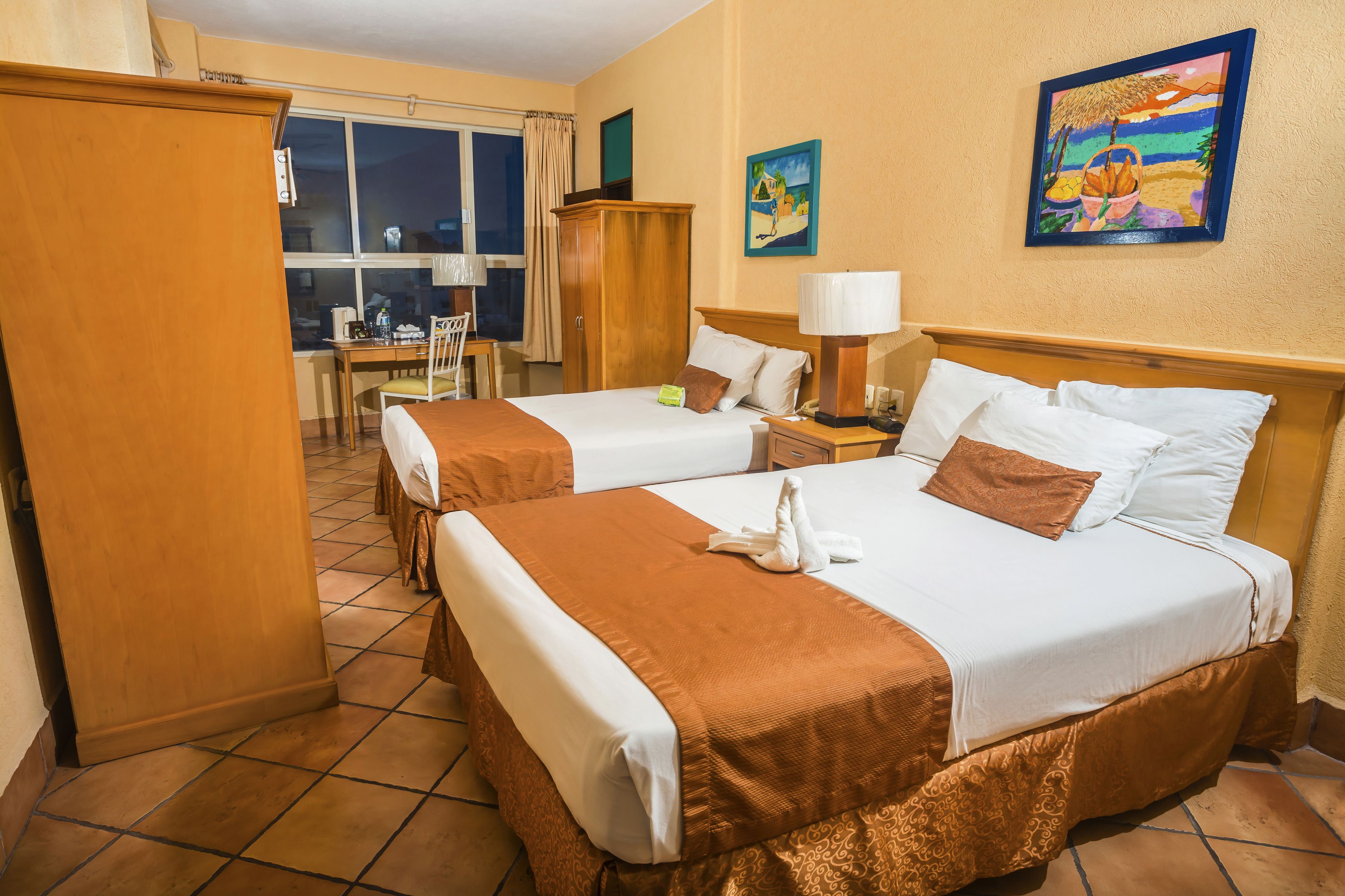 Une chambre d’hôtel avec deux lits, un bureau et une chaise.