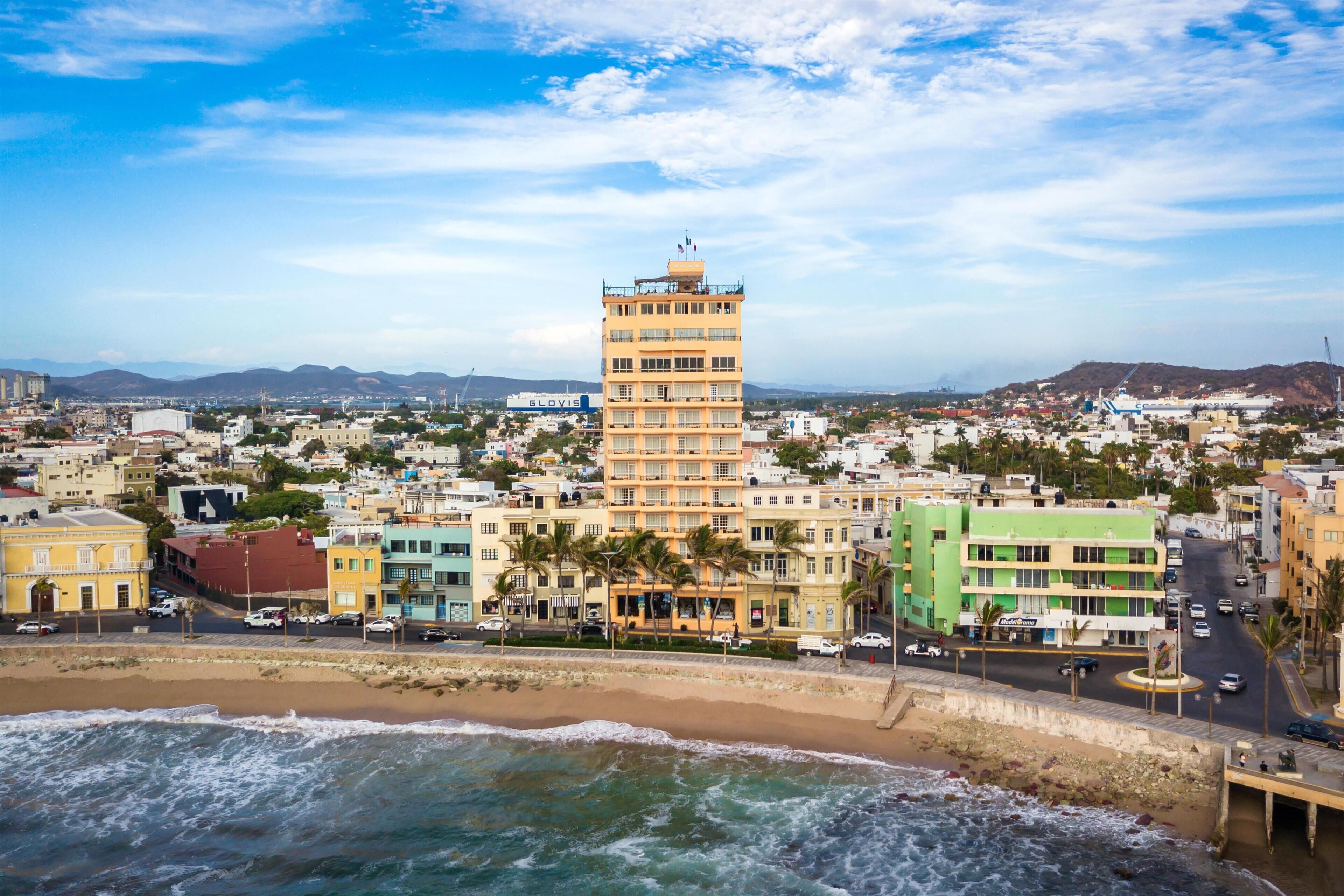 A coastal cityscape with a prominent tower building, a beach, and a mix of residential and commercial buildings.