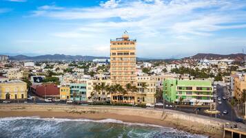 A coastal cityscape with a prominent tower building, a beach, and a mix of residential and commercial buildings.