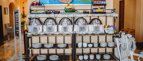 A buffet setup with multiple serving stations, a menu board, and a colorful abstract painting on the wall.