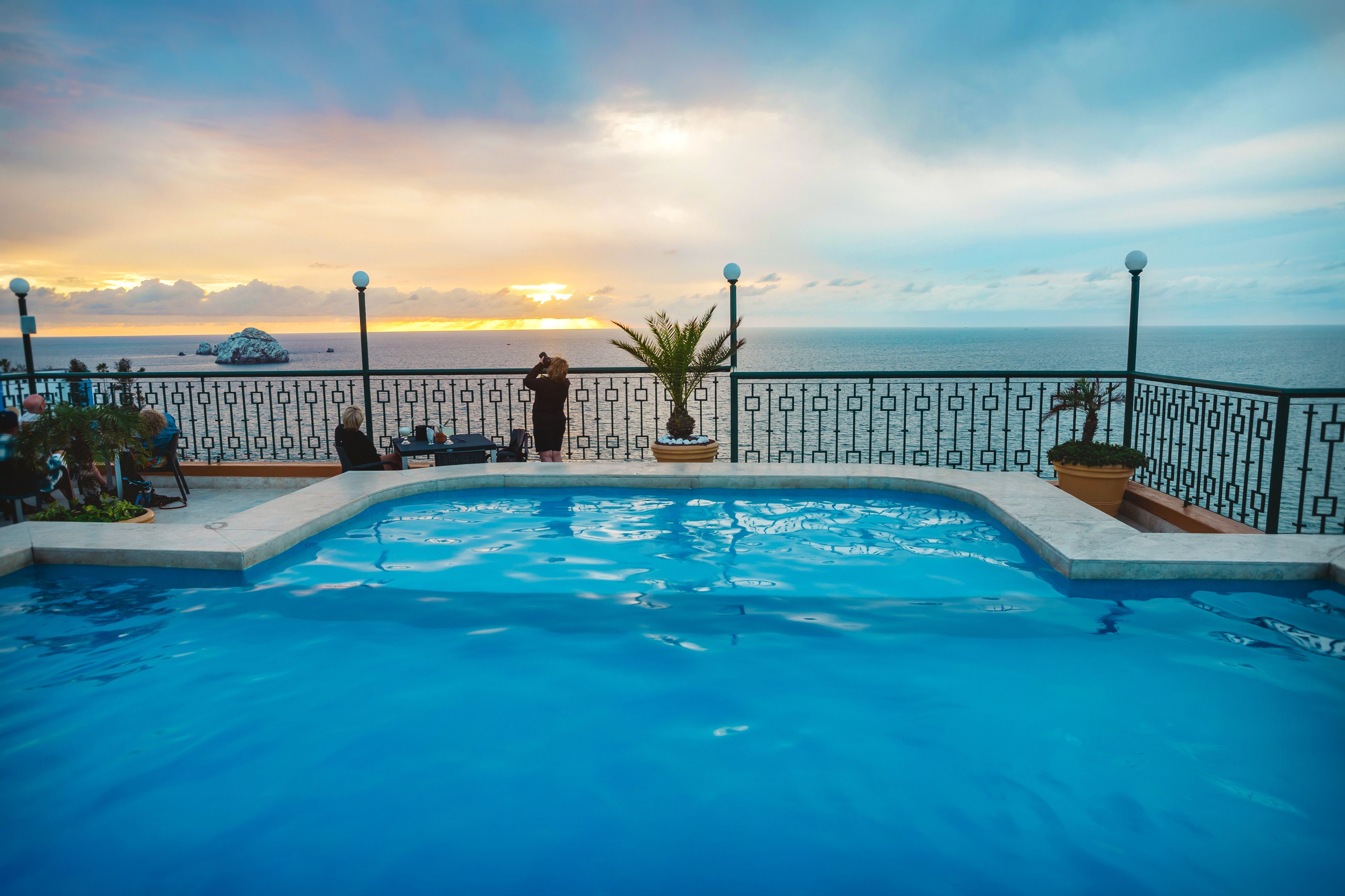 A swimming pool with a view of the sea and sunset.